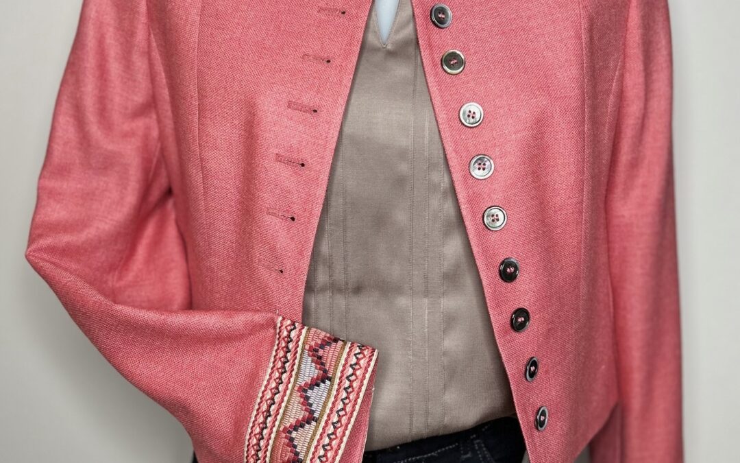 Schaufensterpuppe mit dunkelblauen Jeans, Trachtenbluse glänzend in Farbe Taupe und elegantem Trachtenblazer. Der Blazer ist schlicht unifarben und aufwändige Bordüren zieren die Ärmelabschlüsse. Weitere elegante Trachtenblazer findest du bei Musik & Mode Bürki in Fehraltorf.