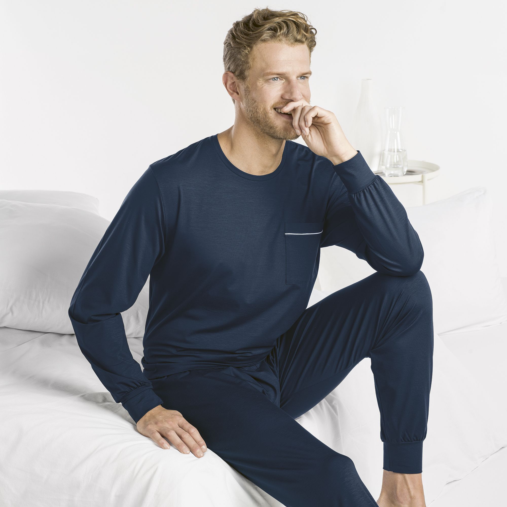 Herren-Pyjama-dunkelblau Blonder Herr in dunkelblauem Pyjama ohne Muster. Hochwertige Nachtwäsche können im Fachgeschäft Musik und Mode Bürki in Fehraltorf gekauft werden.